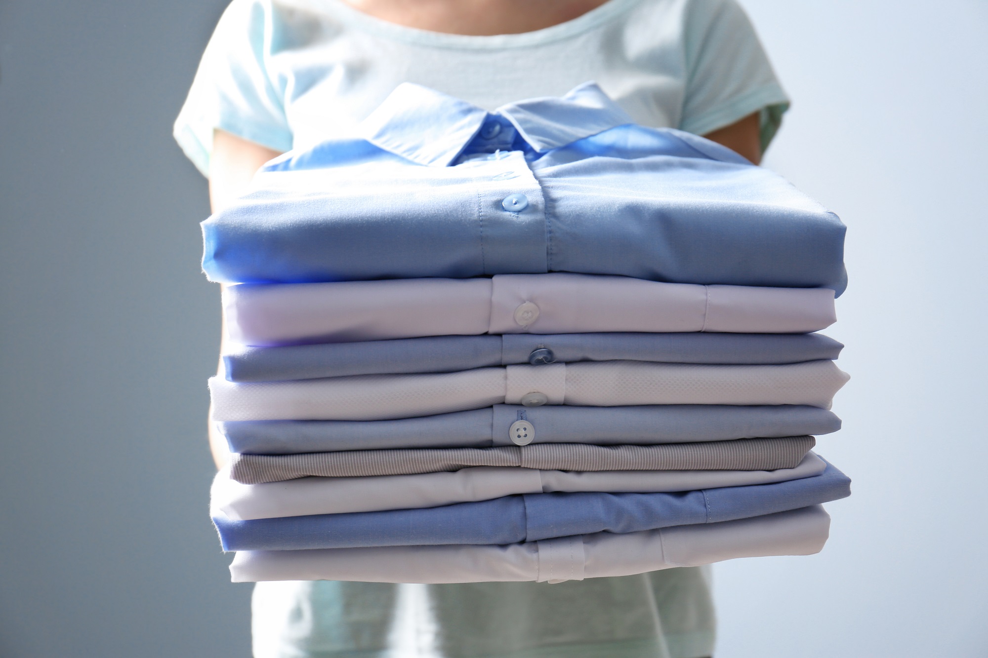 Woman Holding Stack Of Clothes, Closeup